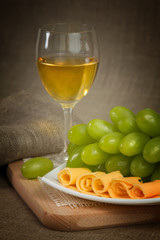 A glass of white wine, green grapes of wine on a wooden surface