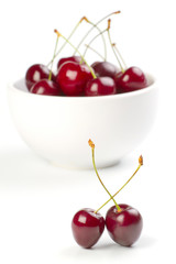 Red ripe cherries in a bowl on white background