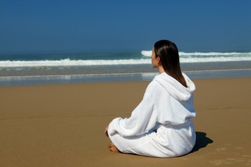 Fototapeta na wymiar Woman in a bathrobe sitting on a beach