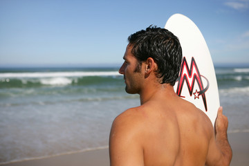 Man with a surfboard looking at the ocean