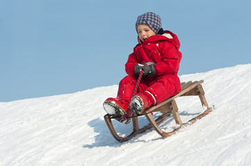 Kid sliding with sledding in the snow.
