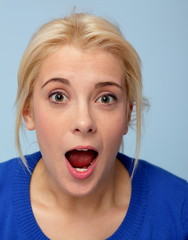 Portrait of beautiful surprised blonde girl on blue