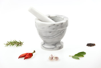 Marble mortar and pestle with herbs and spice on white