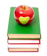 apple with green heart on stack of books