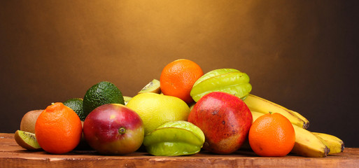 Assortment of exotic fruits on wooden table on brown background