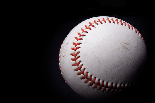 Close up of a baseball over black background