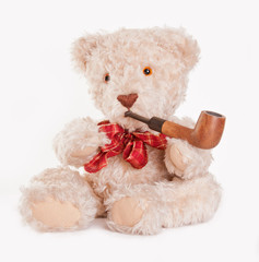 Sitting teddy bear with red bow and wooden pipe