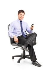 Young businessman sitting on a chair and holding a mobile phone