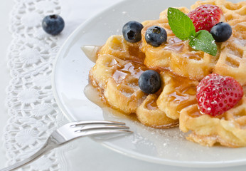Stack of waffles with fruit and honey.