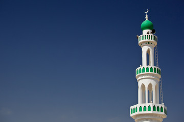 White mosque with minaret against blue sky (Sur, Oman)