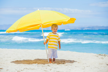 Boy with big umbrella on tropical beach - 39110636