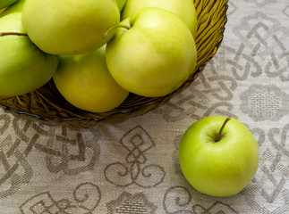 green apples in a glass vase on the table cloth