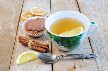 Tea, cupcake, cinnamon sticks and lemon slice
