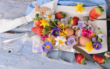 Frohe Ostern: österliches Gedeck mit Früchten und Blumen