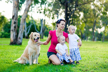Fototapeta premium Mother and her two sons in the park with a golden retriever