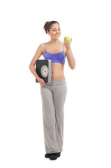 A young and fit woman holding an apple and scales