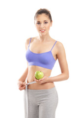 A young and sporty woman holding a fresh green apple