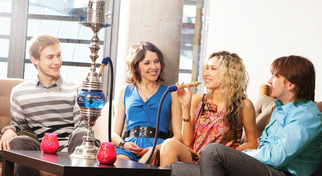 A company relaxing in a restaurant and smoking a hookah