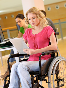 Young woman in wheelchair working in office