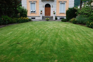 Fototapeta na wymiar Freshly cut lawn in garden in front of an ancient villa, Italy