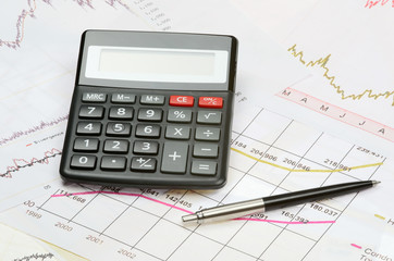 calculator and pen on a financial charts
