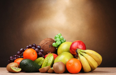 Fototapeta na wymiar Asortyment egzotycznych owoców na drewnianym stole na brązowym tle