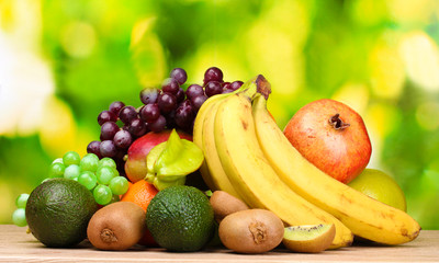 Assortment of exotic fruits on wooden table on green background