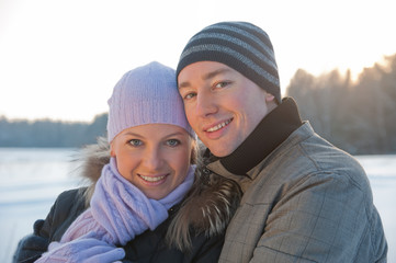 Smiling man and woman at sunlight on the winter background