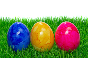 Painted Easter eggs on grass with white background copy space