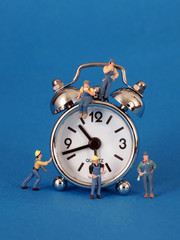 Eine Uhr umgeben von vielen kleinen Arbeitermaennchen....