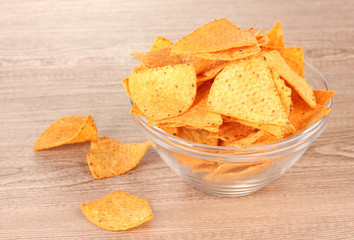 tasty potato chips in transparent bowl on wooden table