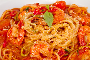 A plate of linguini with sauteed shrimp, tomato, chili  and oliv