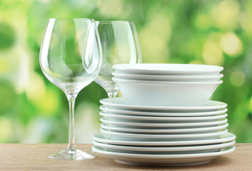 Clean dishes on wooden table on green background