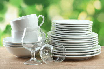 Clean dishes on wooden table on green background