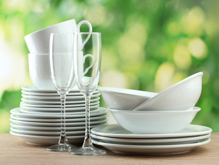 Clean dishes on wooden table on green background