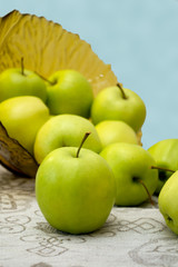 green apples in a glass vase on the table cloth