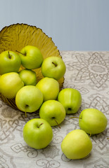 green apples in a glass vase on the table cloth