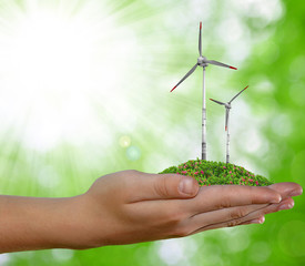 Fototapeta na wymiar wind turbine in hand on green natural background
