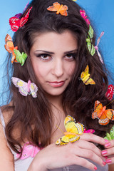 Beautiful girl with butterflies in hair isolated on blue