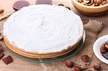 cake on glass stand and nuts on wooden  table