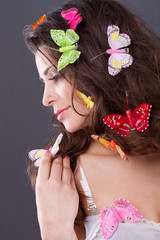 Beautiful girl with butterflies in hair isolated on gray