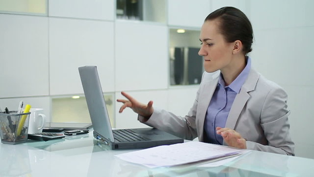 Frustrated businesswoman with laptop in the office, slow motion