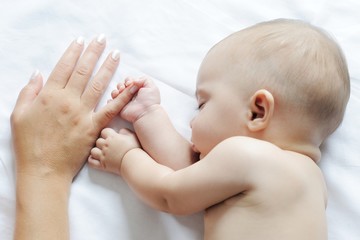 Baby sleeping close to her mother, holding her finger