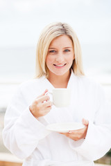 happy young woman in bathrobe drinking coffee