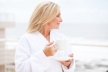 beautiful young woman in bathrobe drinking coffee in the morning