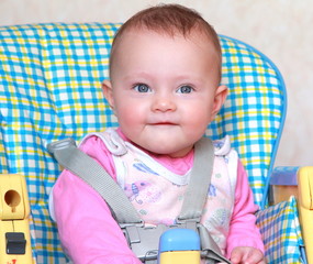 Aborable happy baby girl sitting on the bright baby chair and sm