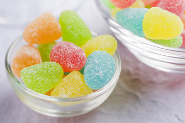 Colored jelly candy in glass bowls on a blue background