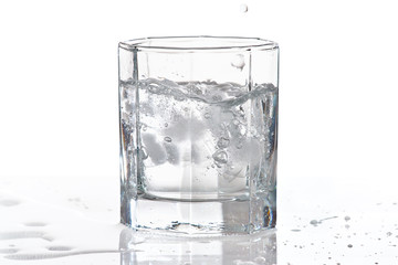 Glass of water and ice with splash on a white background