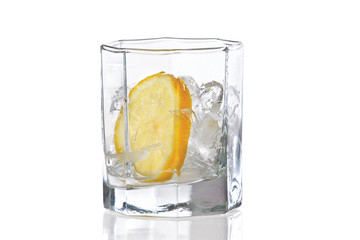 Glass with ice and slice of fresh lemon on a white background