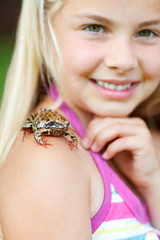 little girl with a frog on her shoulder